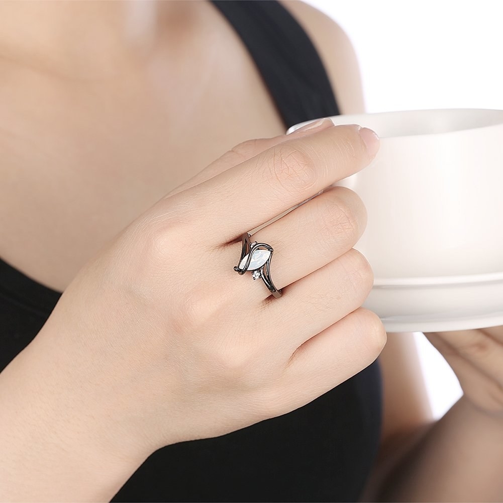 A black opal ring on a hand holding a mug.