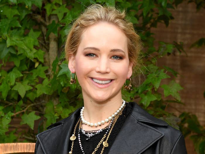 Jennifer smiles while wearing a black moto leather jacket and layered necklaces