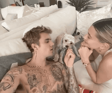 Justin Bieber and Hailey Bieber play with a dog on their couch in this gif