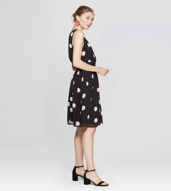 a model wearing a black dress with black block heels