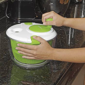 a model turning the handle on the lid of the salad spinner 