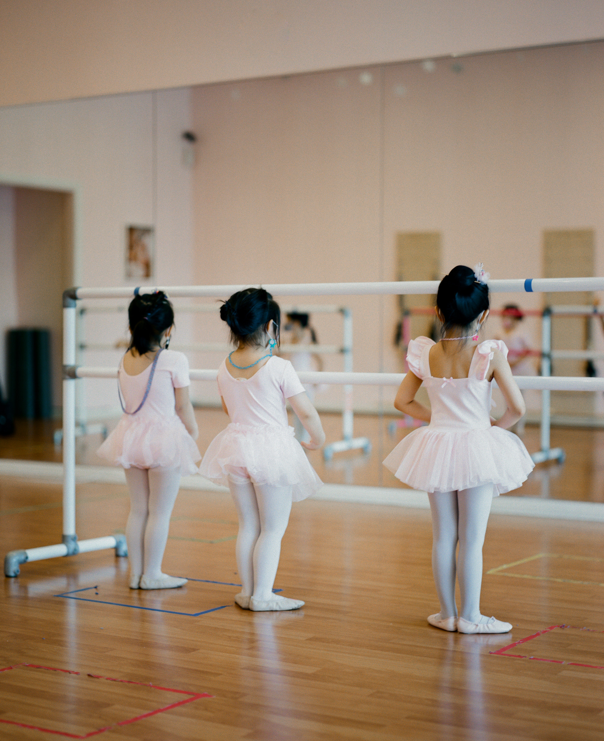 Three young girls in ballet costumes in a classroom 