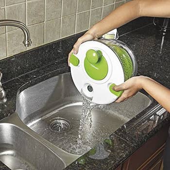 a model pouring water out off the drainage holes on the lid of the salad spinner 