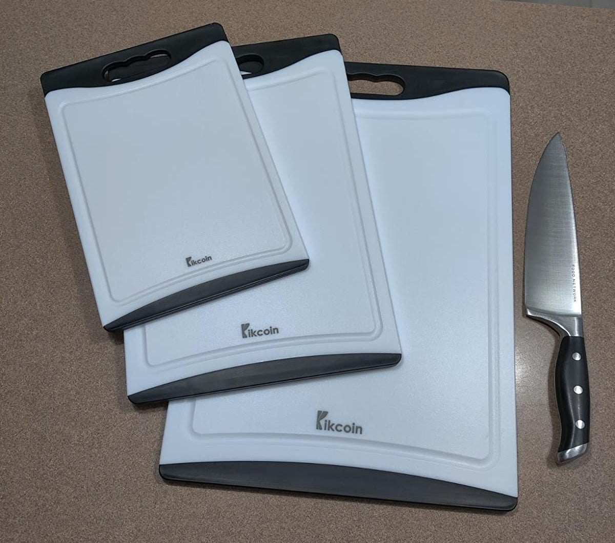 a reviewer photo of the three different-sized cutting boards sitting next to a knife
