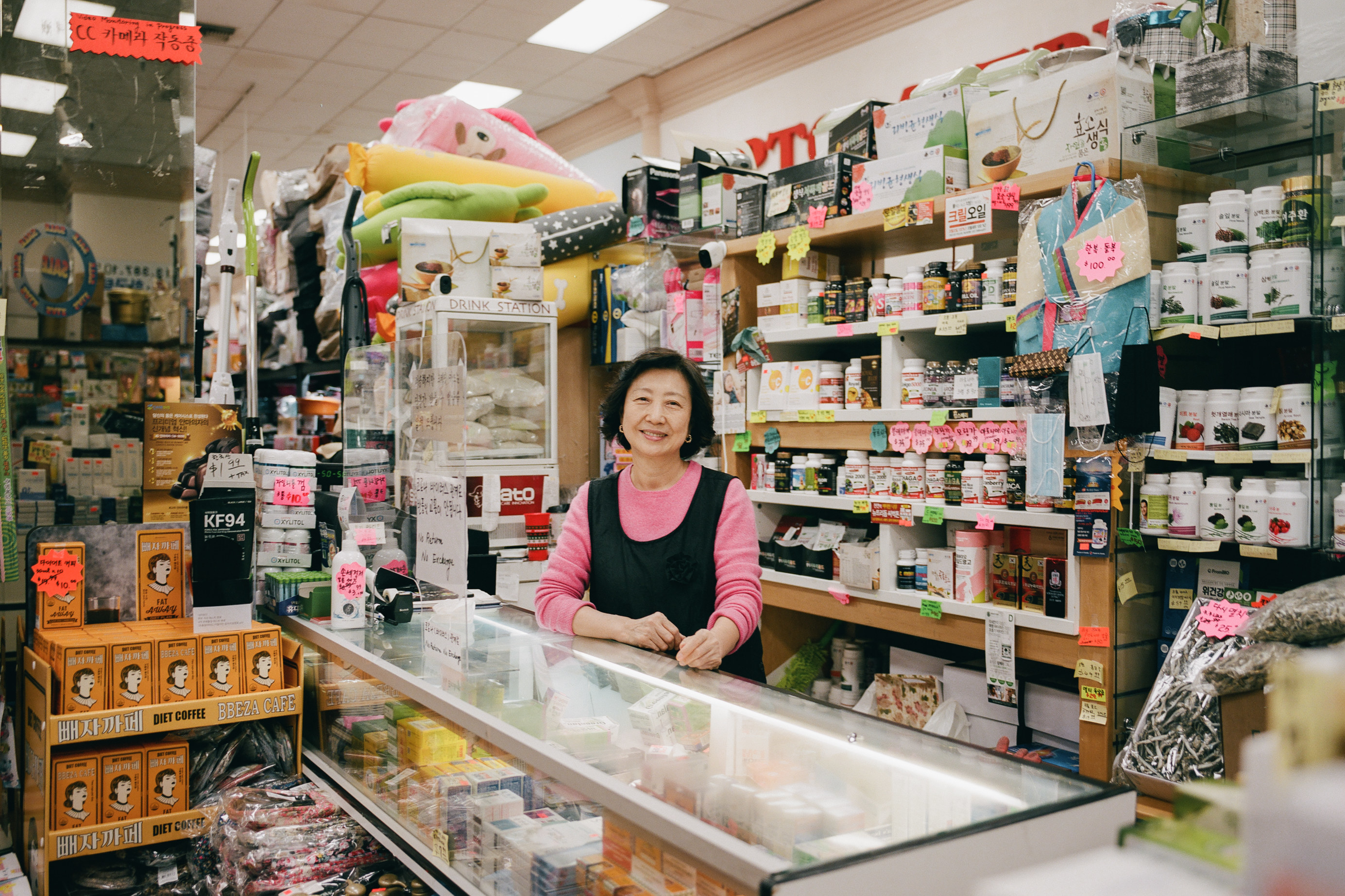 A woman smiling behind a counter of a very full home goods store