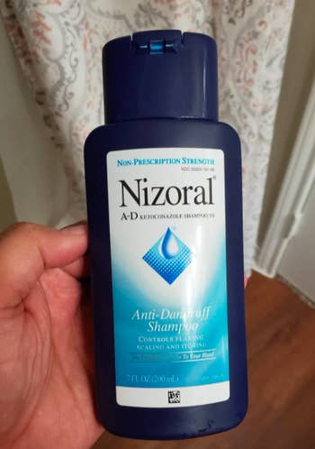 A customer review photo of them holding the bottle of Nizoral anti-dandruff shampoo