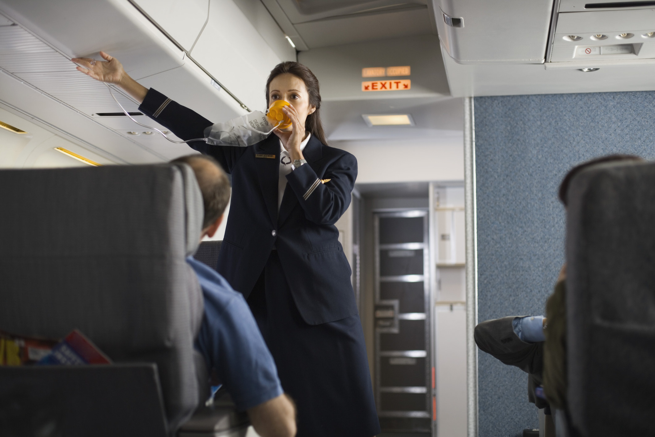 A flight attendant demonstrating the oxygen mask