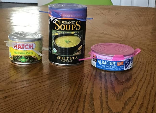 a reviewer photo of three cans each with a silicone lid on top 