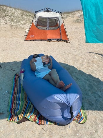 a reviewer laying on the blue lounger reading a book