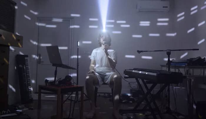 Bo Burnham wears a light on his head that illuminates around the darkened room as he sings "Content" in "Inside"