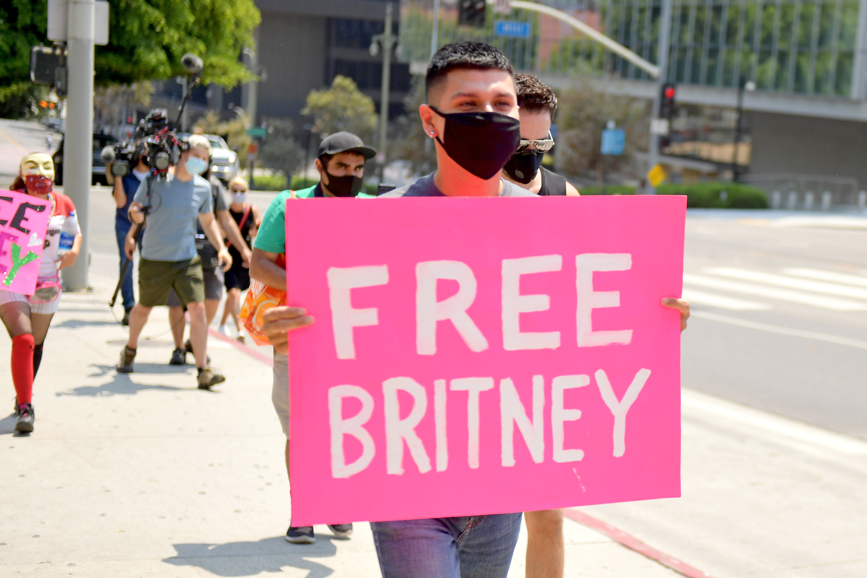 A person walking with a "Free Britney" poster