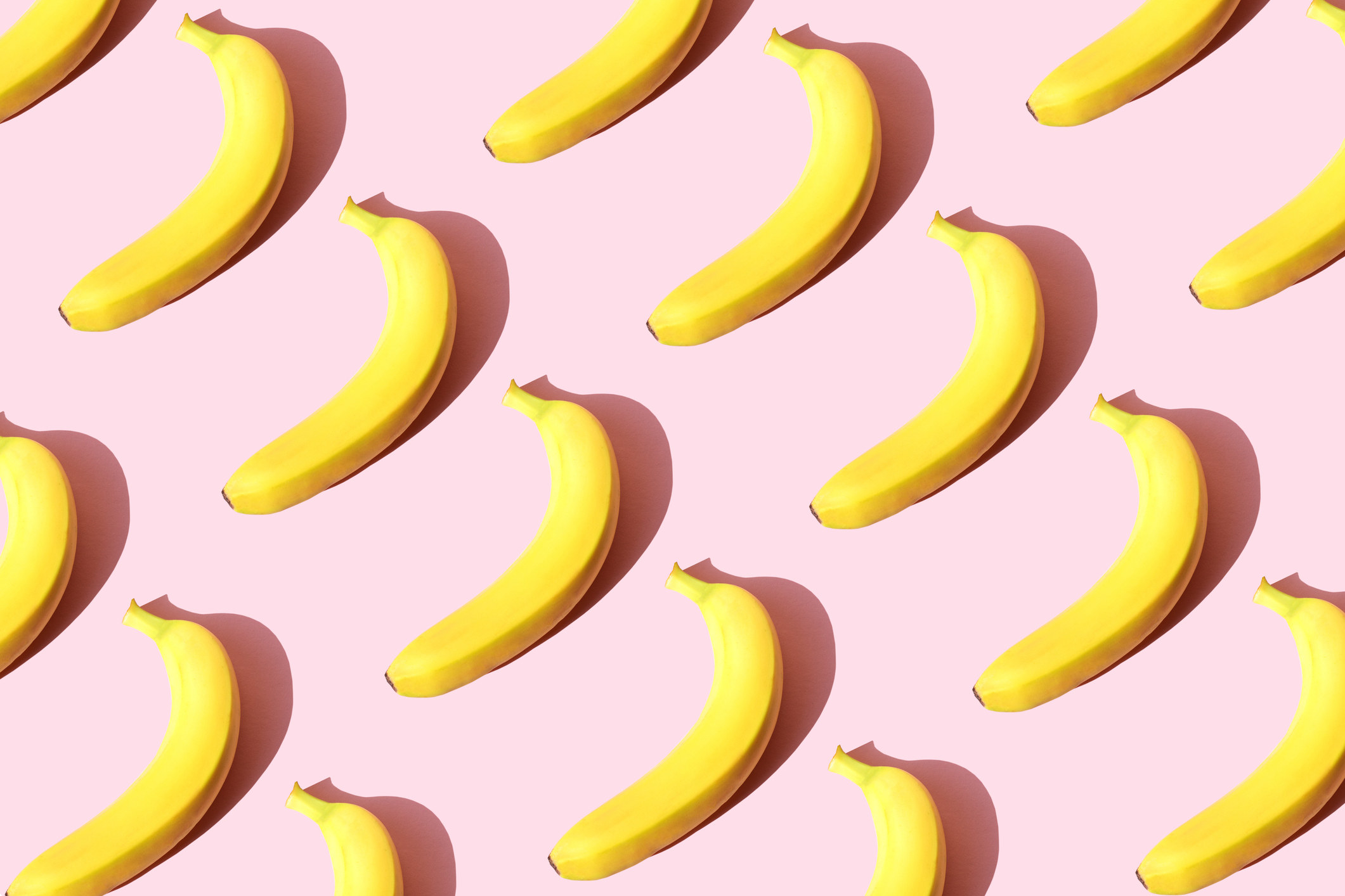 Several bananas arranged neatly in rows on a solid background