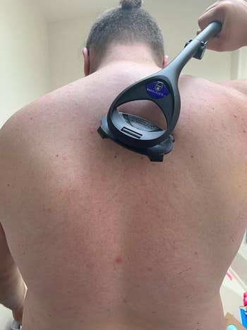 A reviewer photo of a person using the back shaver on their back