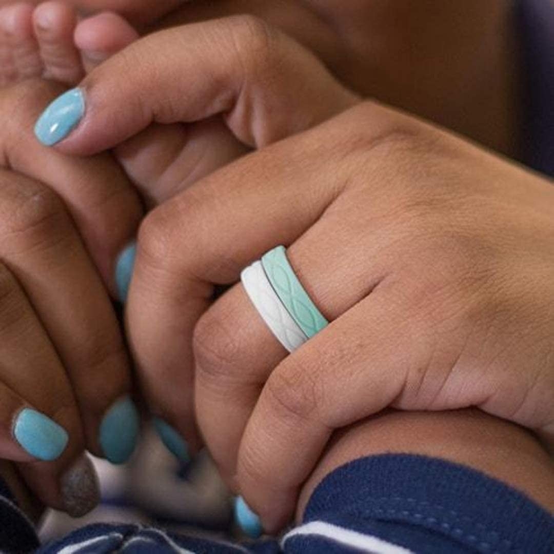 person sitting with a white and blue versions of the ring on their ring finger