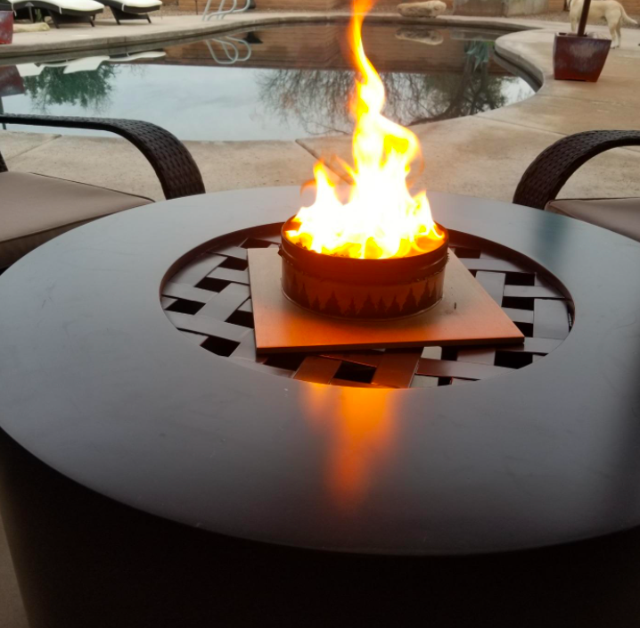 reviewer&#x27;s portable campfire on top of a backyard deck table which is beside a backyard pool