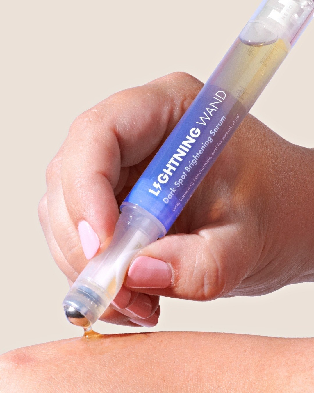 A person rolling the serum over their hand using the rollerball tip