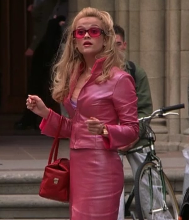 Elle wears a pink jacket with matching skirt, and pink-shaded glasses
