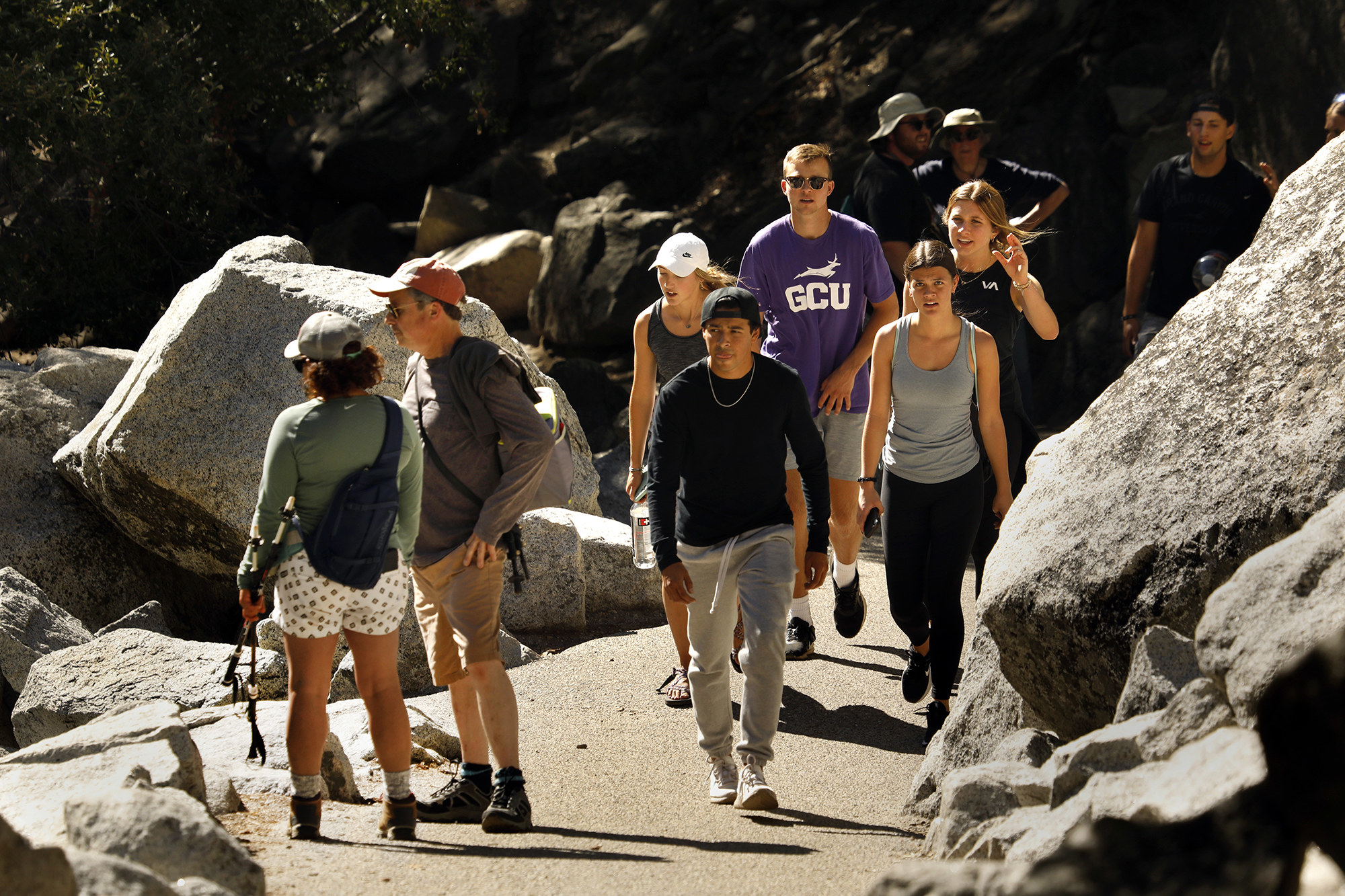 Groups of people, most unmasked, walking up a hiking trail in Yosemite National Park