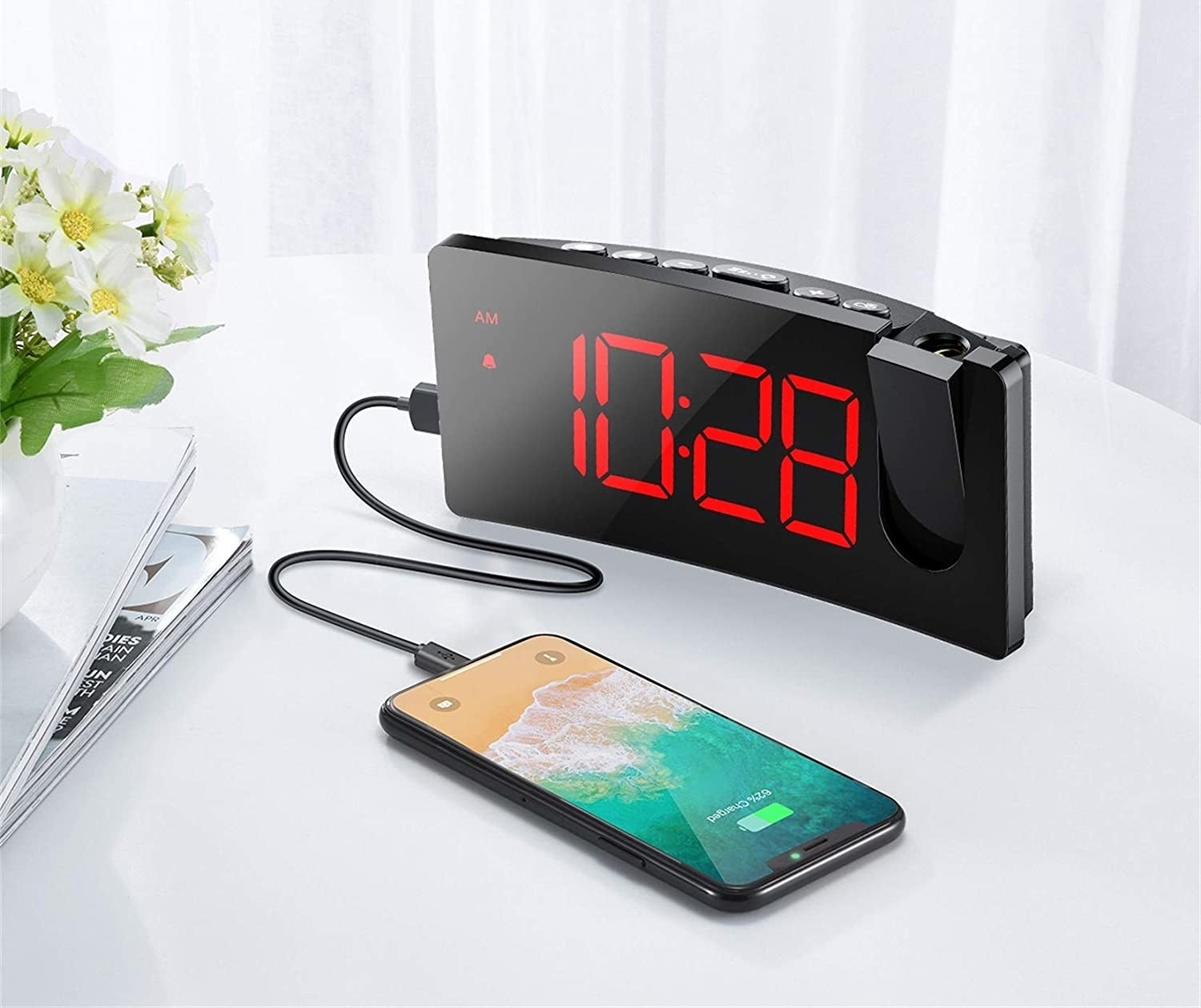 A curved alarm clock with a cell phone plugged in and charging