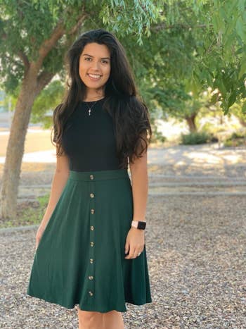 Reviewer wearing dress with black top and green skirt