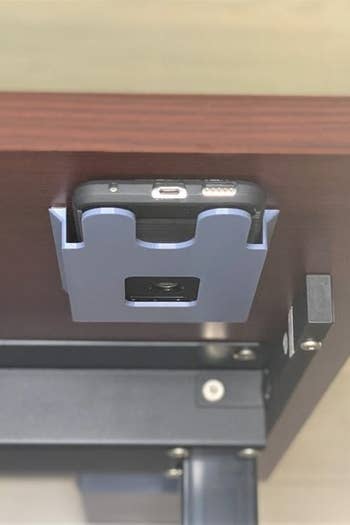 the shelf installed under a desk with a smartphone inside 