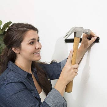 A person nailing in a bracket into the wall