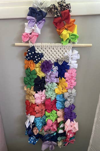 Reviewer's photo of macarame hair accessory holder holding many hair ties and bows
