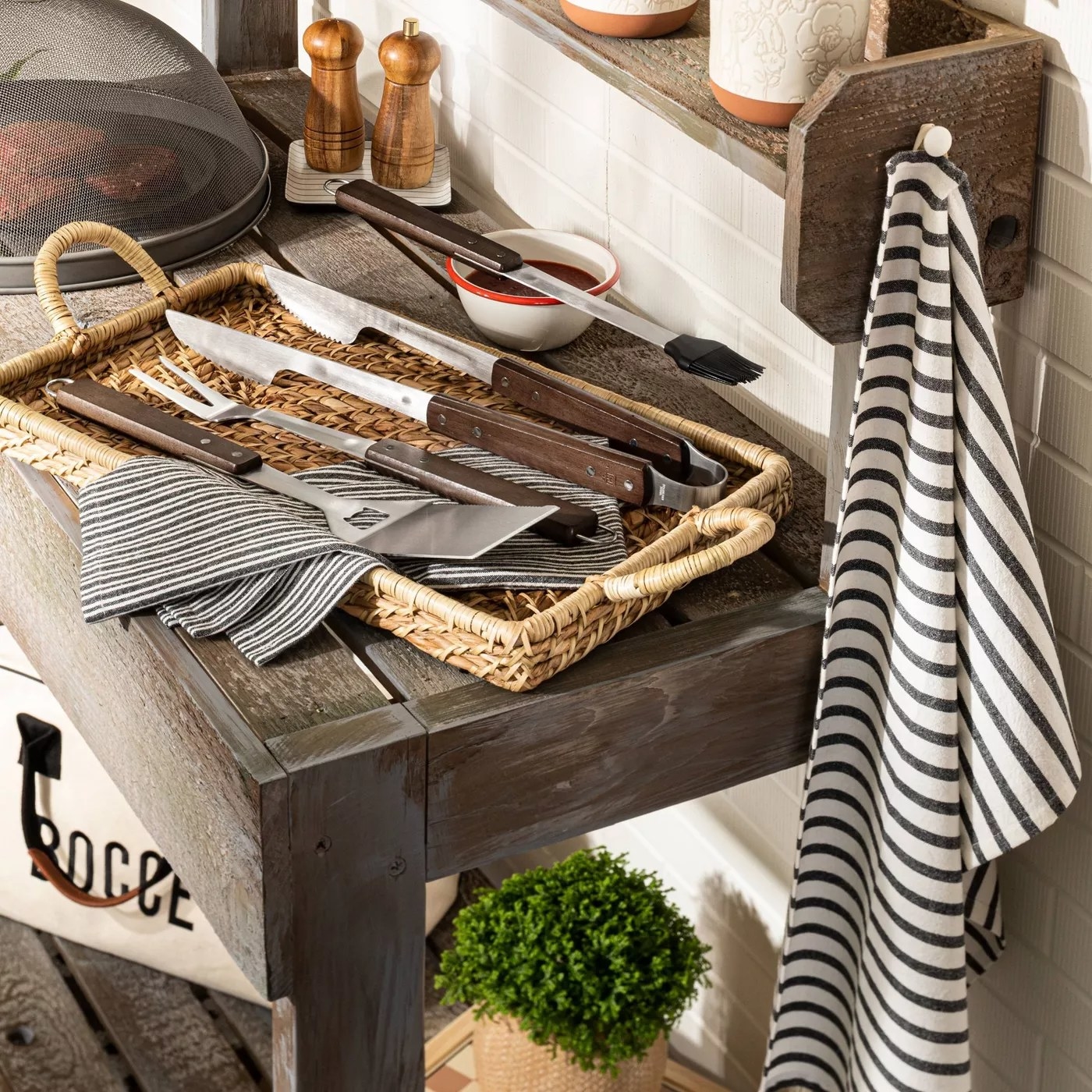 The grilling set with the four wooden and metal tools next to a grill