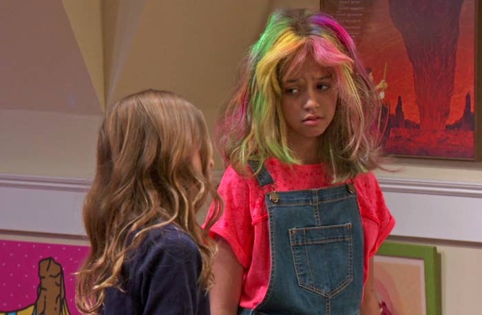 Sydney furrows her brows, concerned, as she rocks a rianbow hairdo