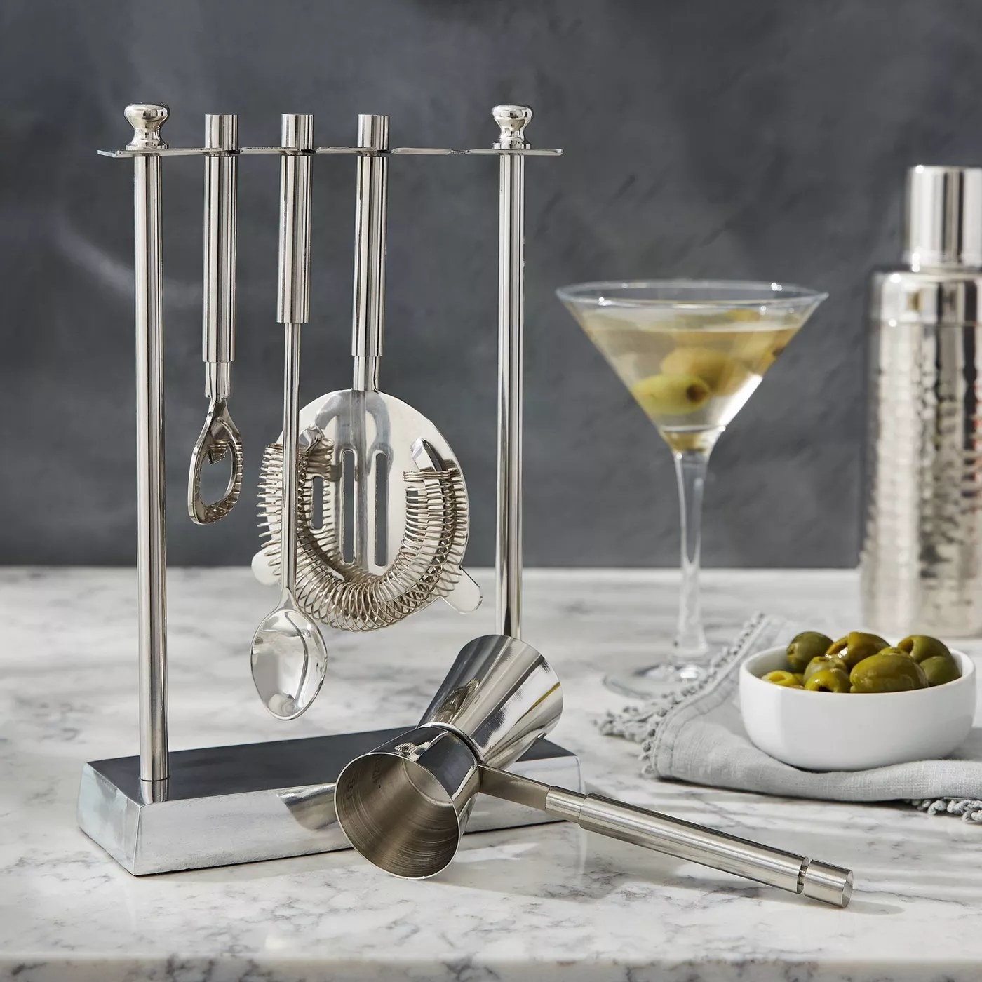 The silver cocktail set and a matching stand on a marble countertop