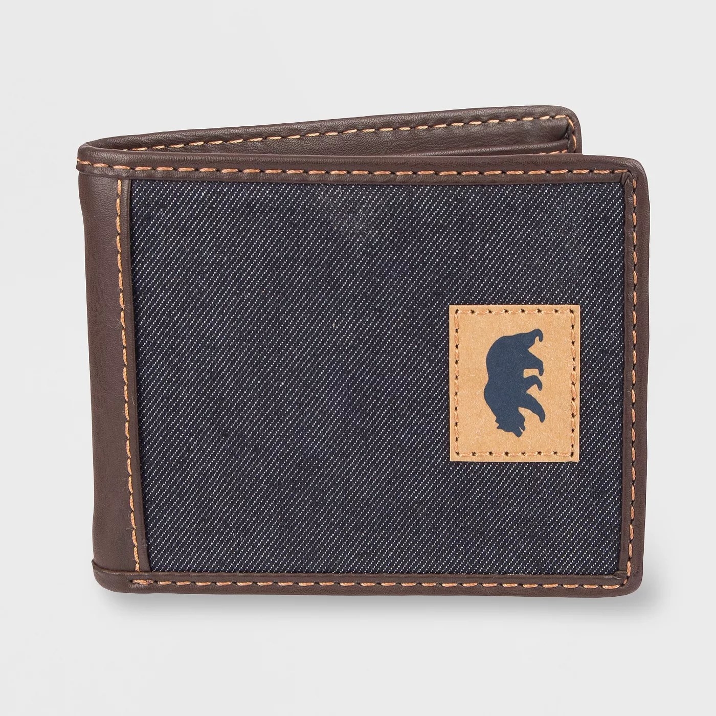 The denim wallet with brown leather trim and a leather bear accent