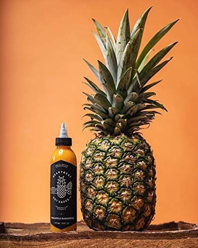 The bottle of Heartbeat Hot Sauce - Pineapple Habanero next to a pineapple