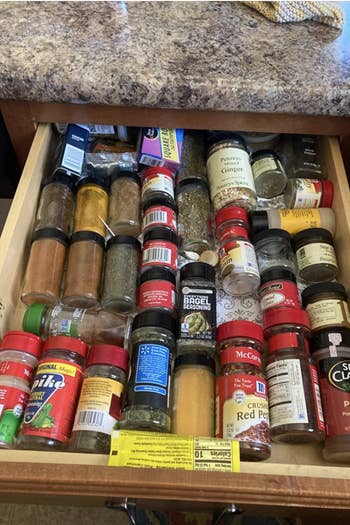 Reviewer's before photo shows an unorganized and messy drawer filled with spice jars