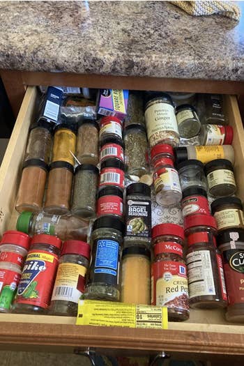 Reviewer's before photo shows an unorganized and messy drawer filled with spice jars