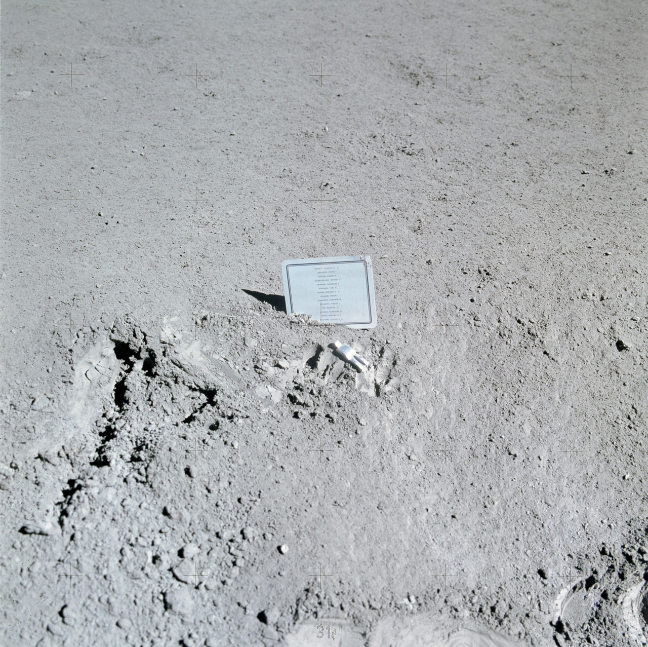 A small metal plaque stuck simply in moon dirt