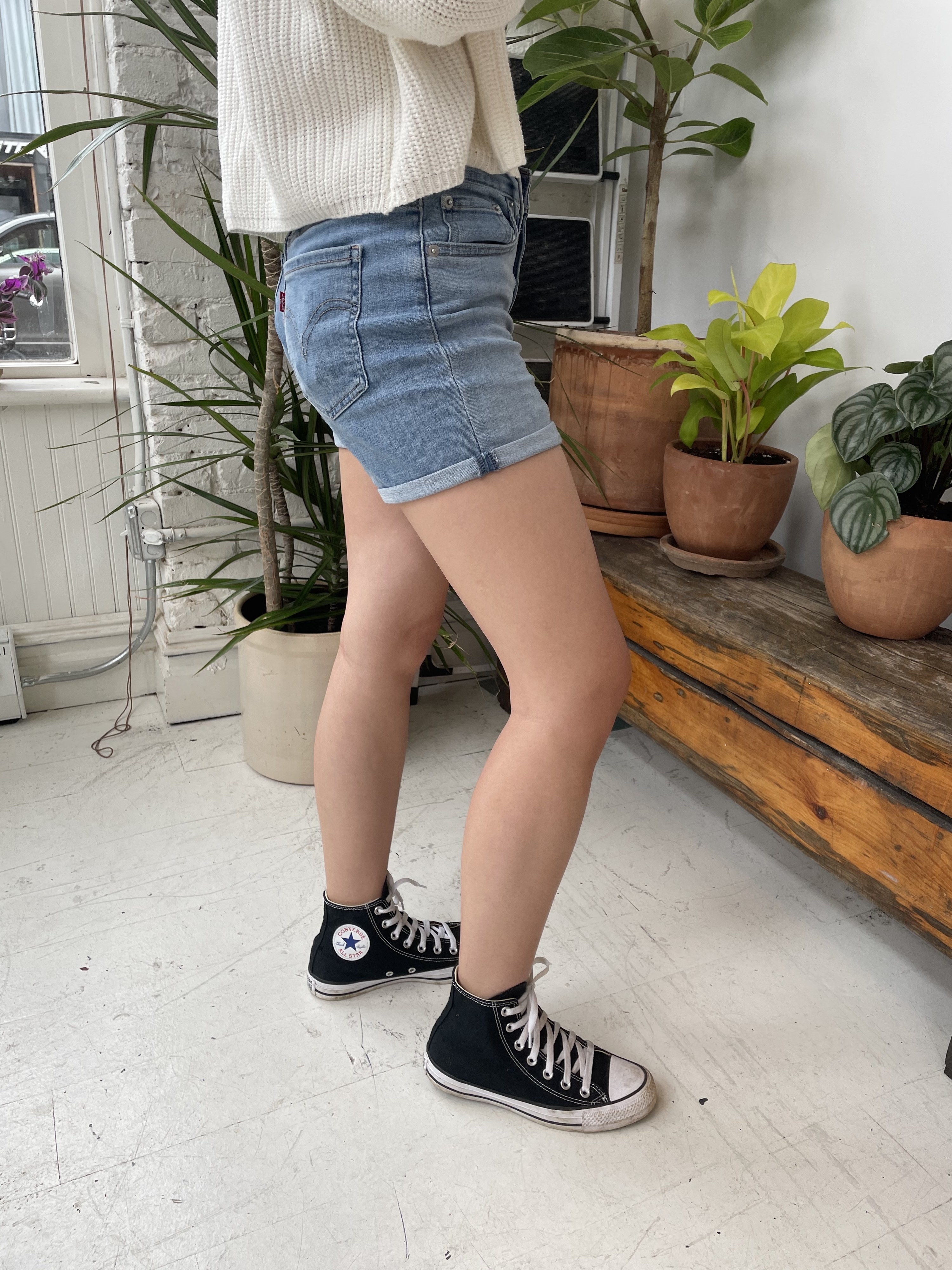 writer wearing the shorts with hi-top black converse, plants in the background