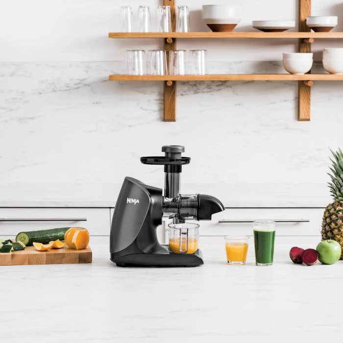 The black juicer on a kitchen counter making fresh juice