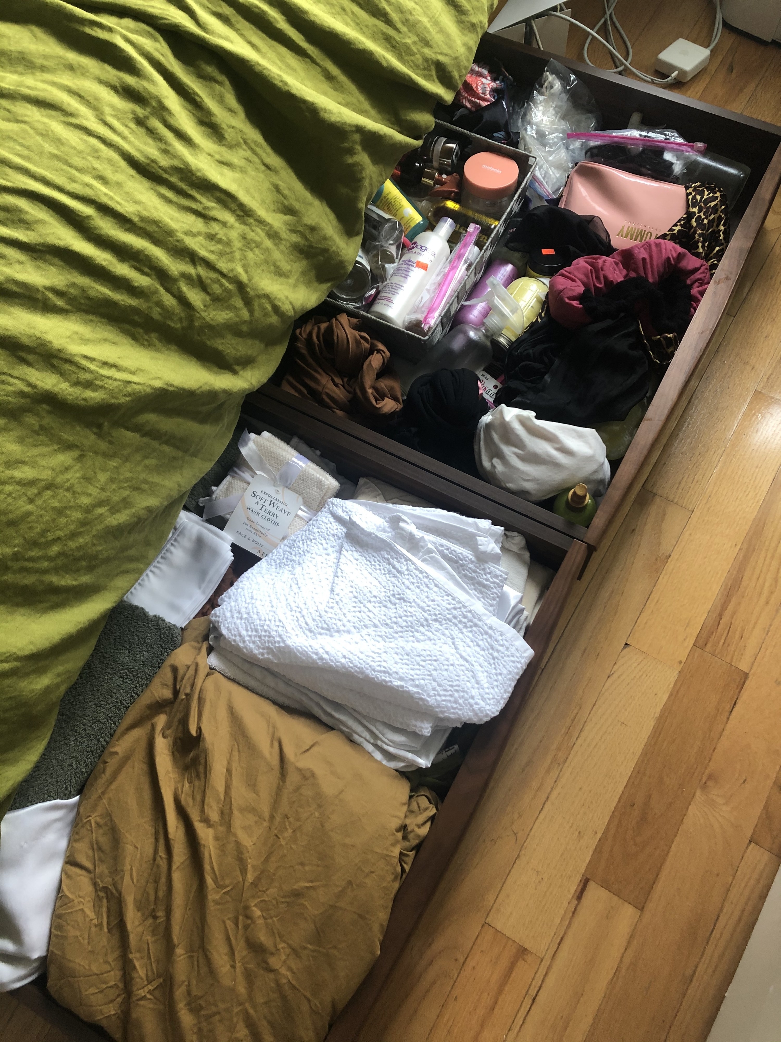 The rolling drawers holding linens underneath a bed