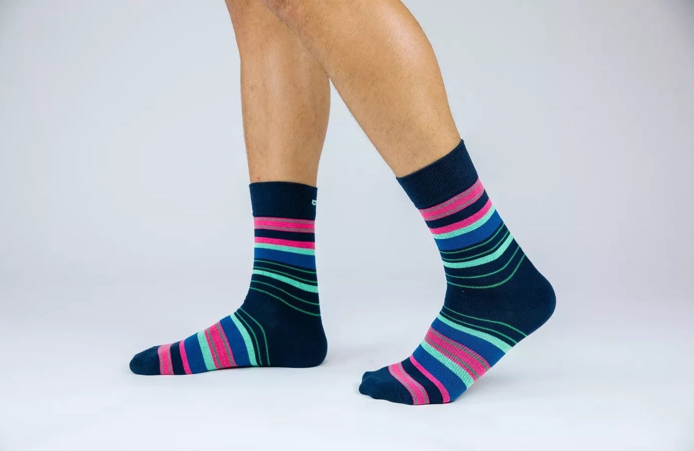 An adult model wearing a pair of the socks with multi-colored stripes
