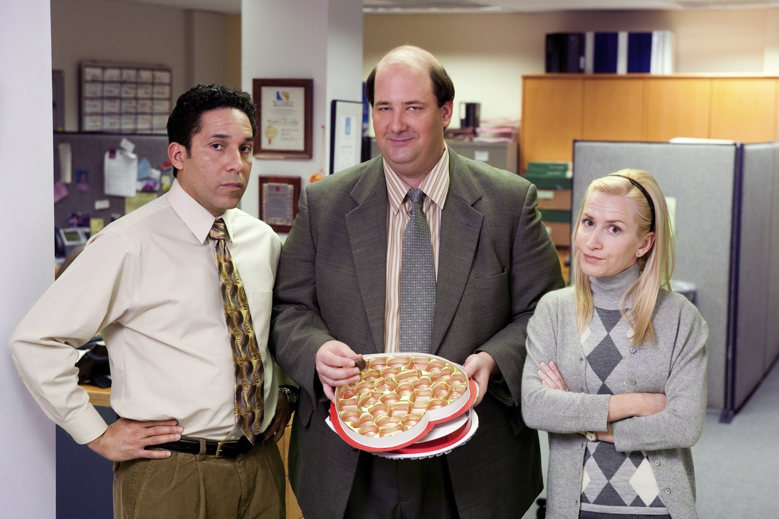 Kevin holds a box of chocolate next to his co-workers on The Office