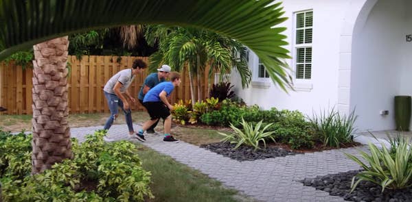 Three boys trying to walk stealthily toward a house window in "Swiped"