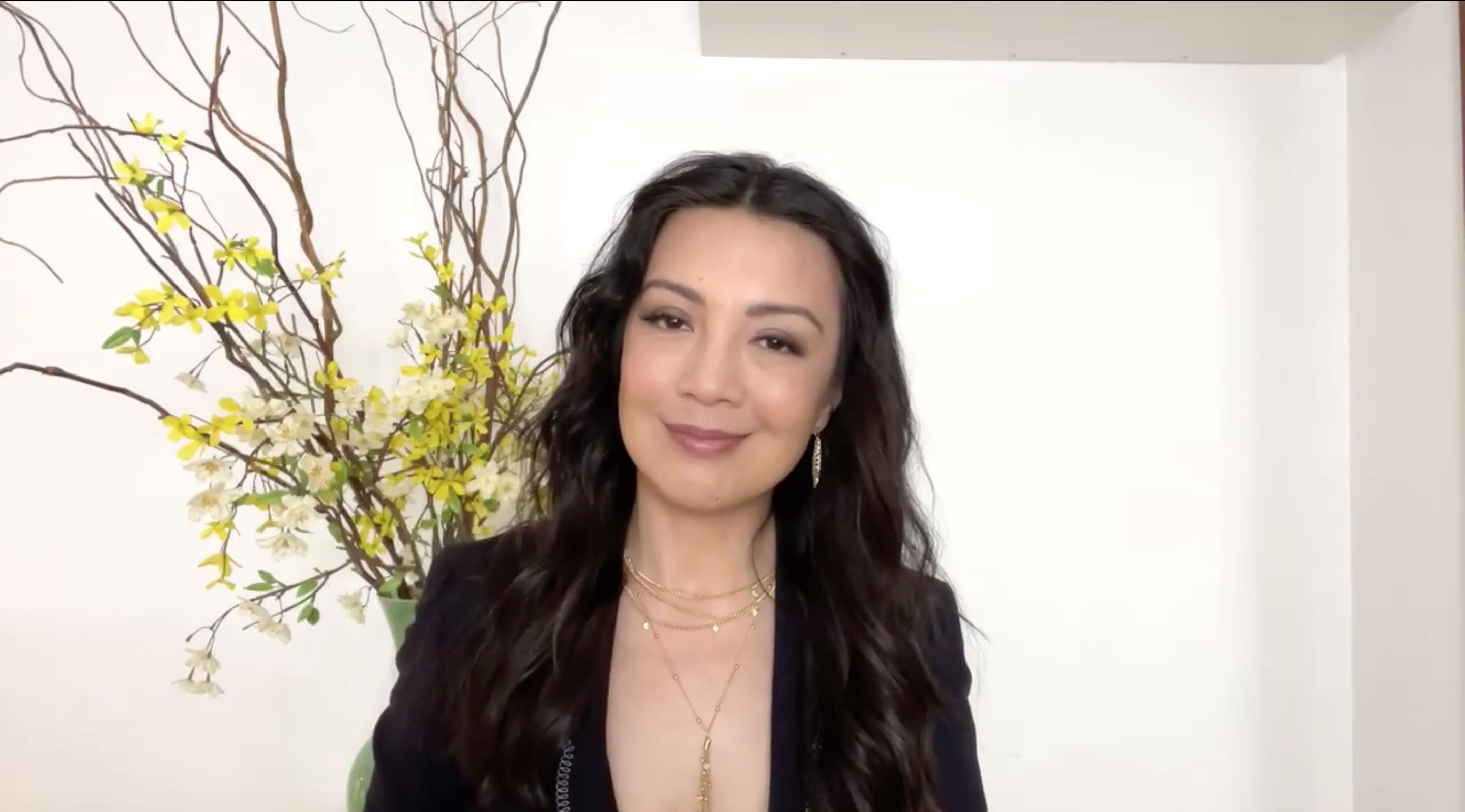 Ming-Na Wen smiles in front of a plant
