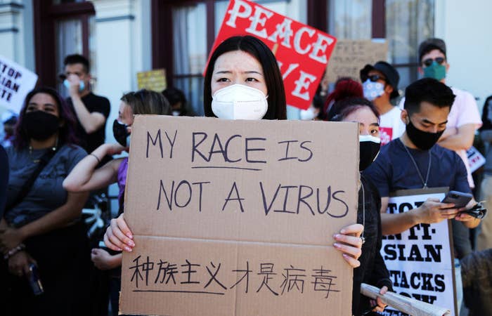 People demonstrate against anti-Asian violence and racism. An Asian woman is holding a sign that says "My race is not a virus"