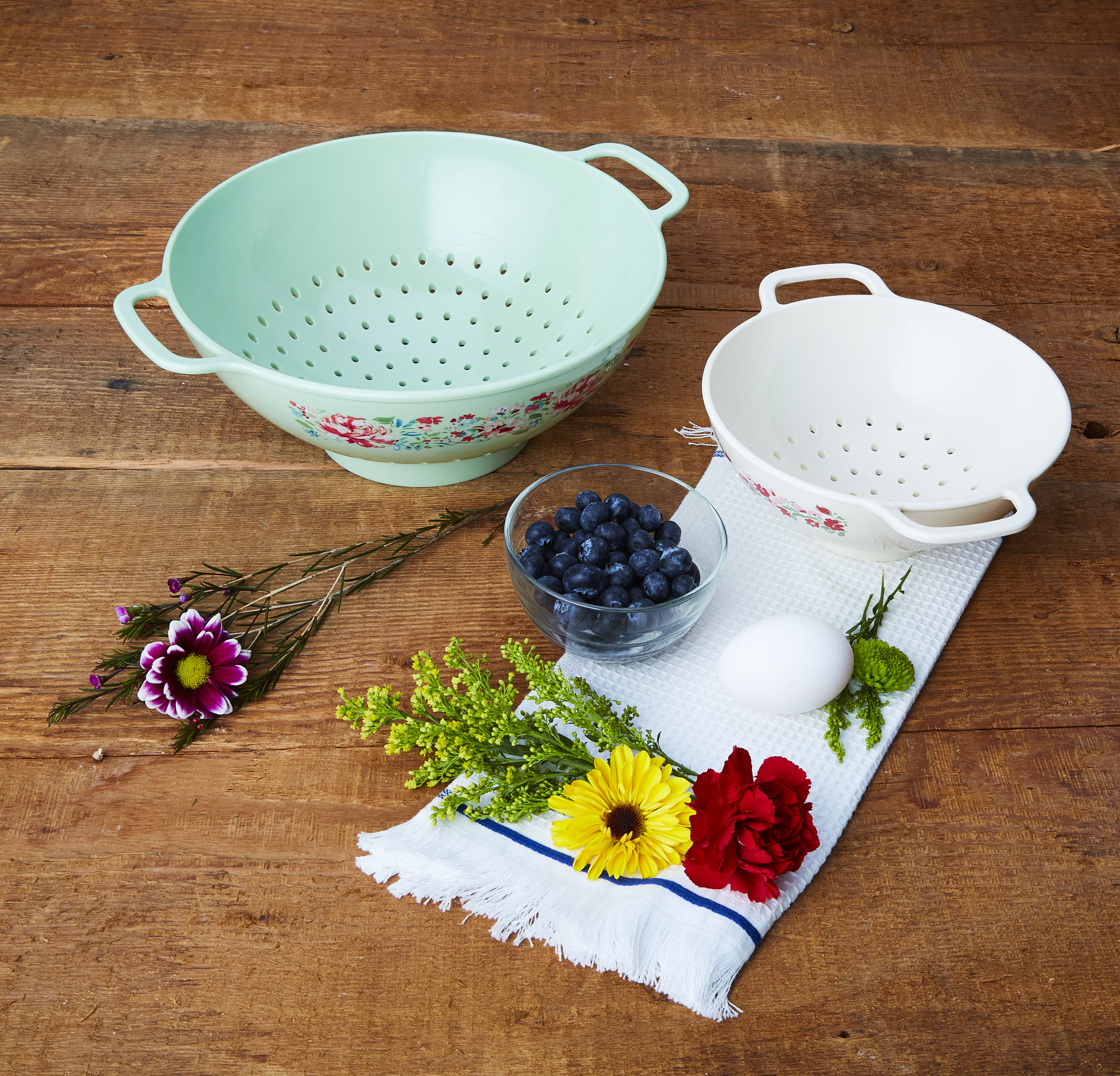 a light blue colander and a white colander with florals on them