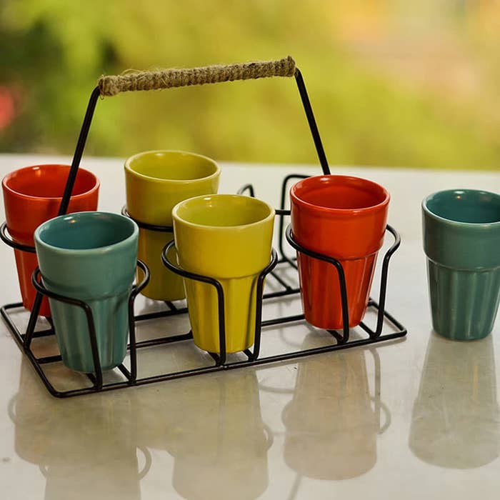 A tea-holder with different coloured cutting chai cups in it 