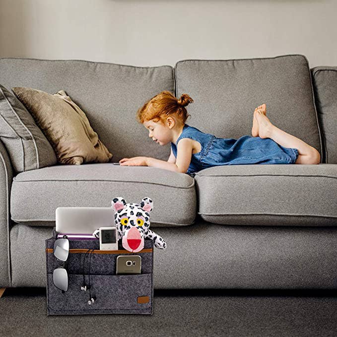 A child lounging on the couch with the couch caddy attached to it. 