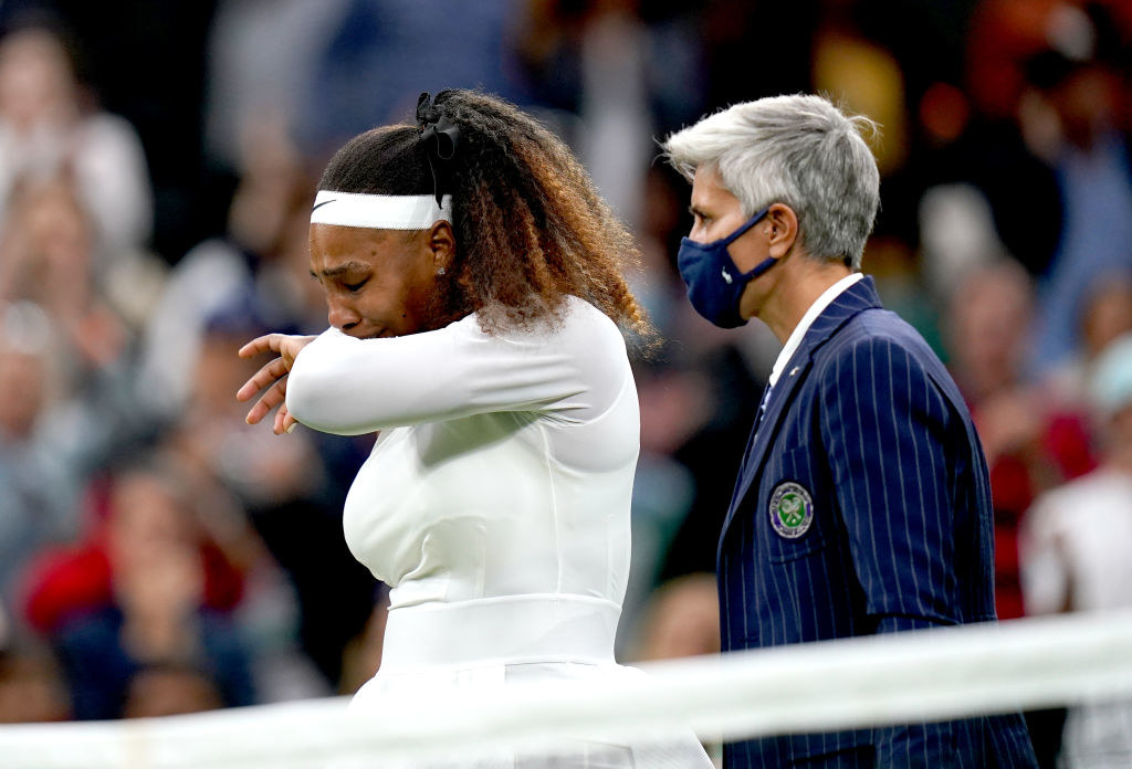 Serena Williams tries to hold back tears as she stands next to the umpire after injuring her right leg during her match