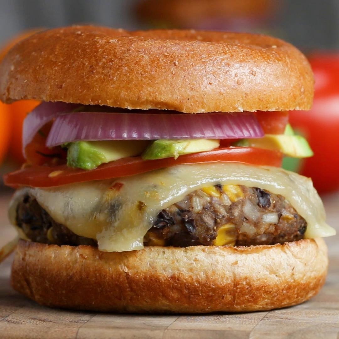 A black bean and corn burger on a bun with veggies and cheese