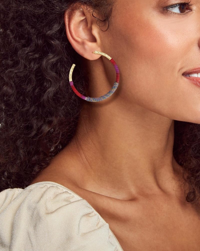 a model wearing hoop earrings with colorful string around them