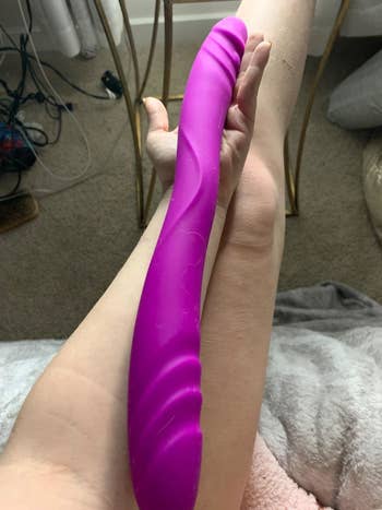 Model holding purple dual-ended dildo to compare length to leg